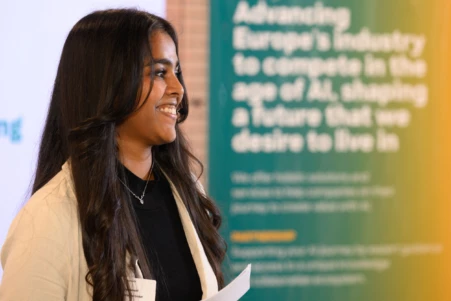 Indian Woman standing on stage doing the moderation of the GenAI Conference 2024
