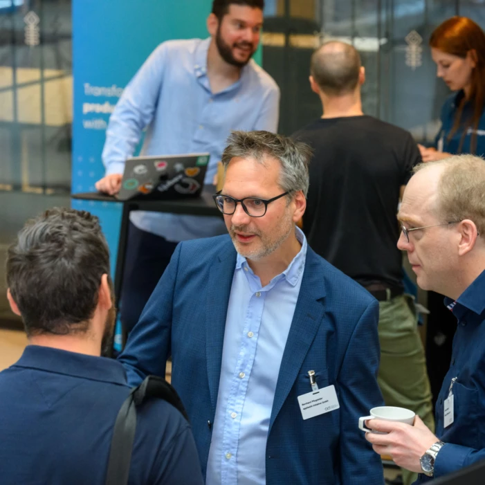 Three men are discussing AI at a conference