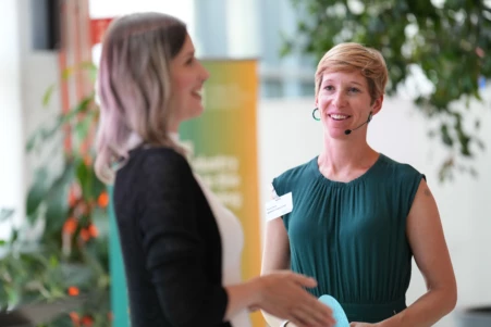 Zwei Frauen diskutieren auf der Bühne einer Konferenz über KI.