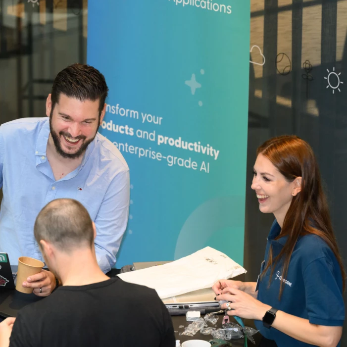 Two men and a women are discussing AI at a booth during a conference.